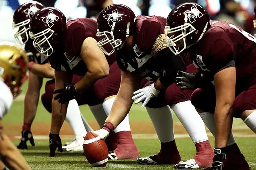 A group of football players are lined up to take the snap.